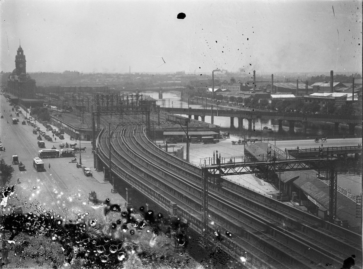 Scene looking towards Flinders Street Station, giving view of Yarra River, train tracks, trams and horse drawn carts, Melbourne City (c. 1920)
