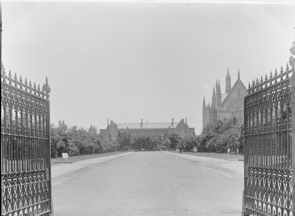 Entrance to University of Melbourne, showing open iron gates, Wilson Hall to the right, Parkville (c. 1920)