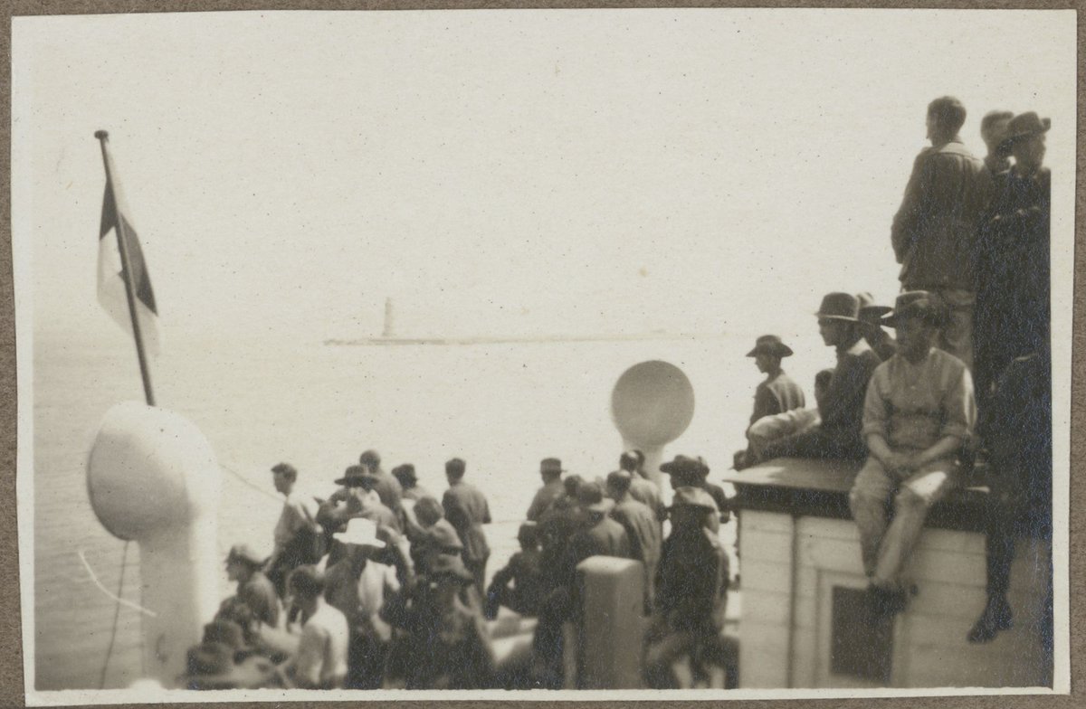Soldiers crowding the deck of the Chemnitz, enroute to Melbourne from Europe, lighthouse in the distance (1919)