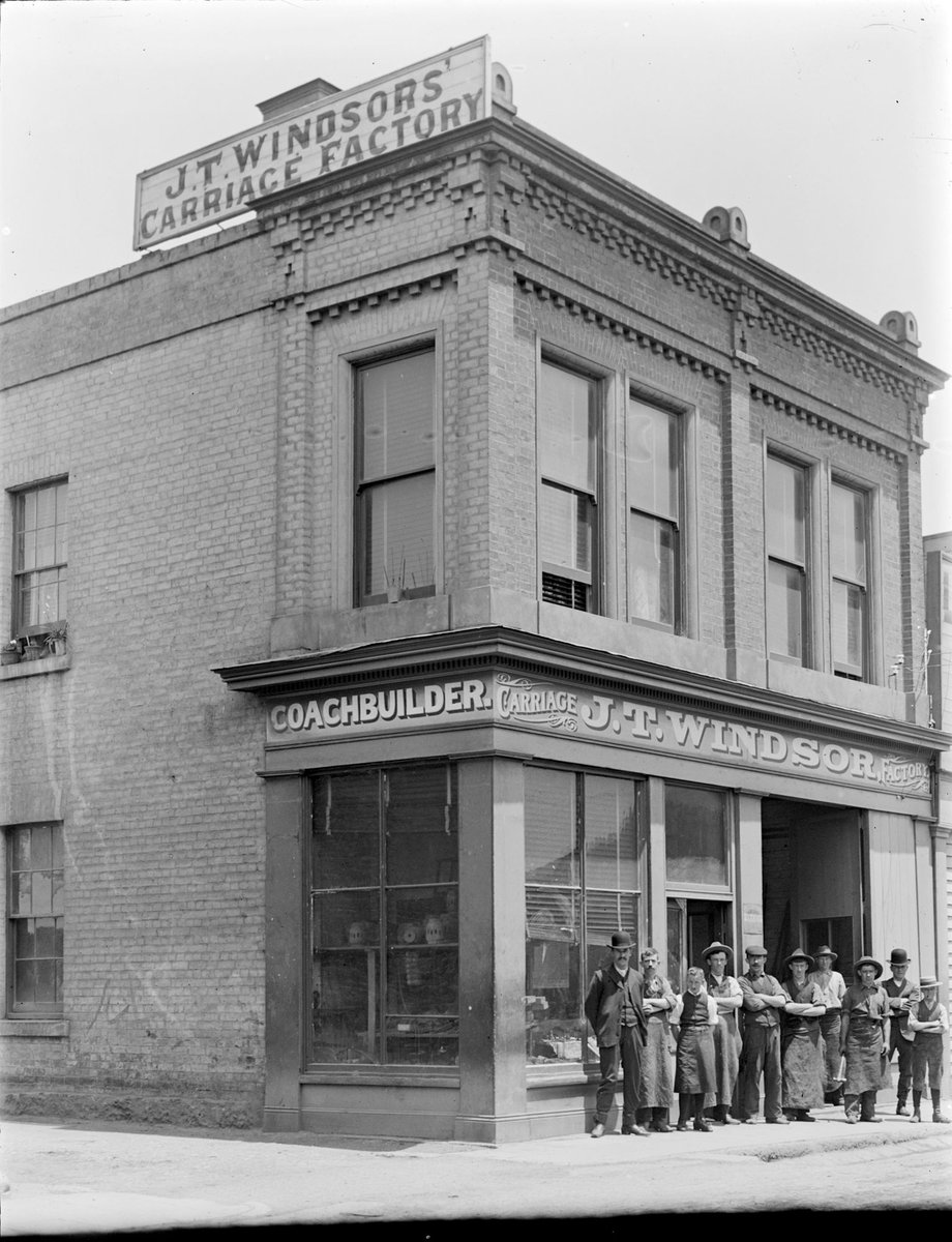 Brick building of two stories with group of nine men and a woman, probably employees of J. T. Windsor's carriage factory (1880–1920)