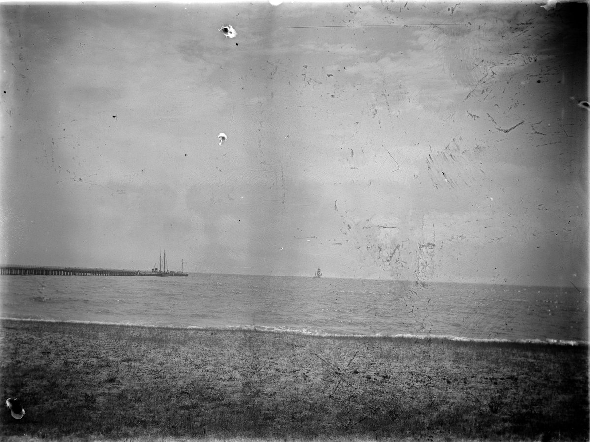 View across Port Phillip Bay, with ships moored at the jetty (1900–20)