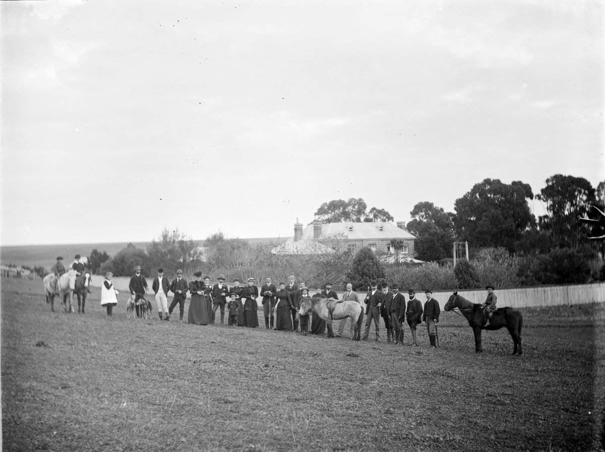Hunt Club on River Flats at Kew. Group of men, women and children, some with horses, standing in a line (1890–1910)