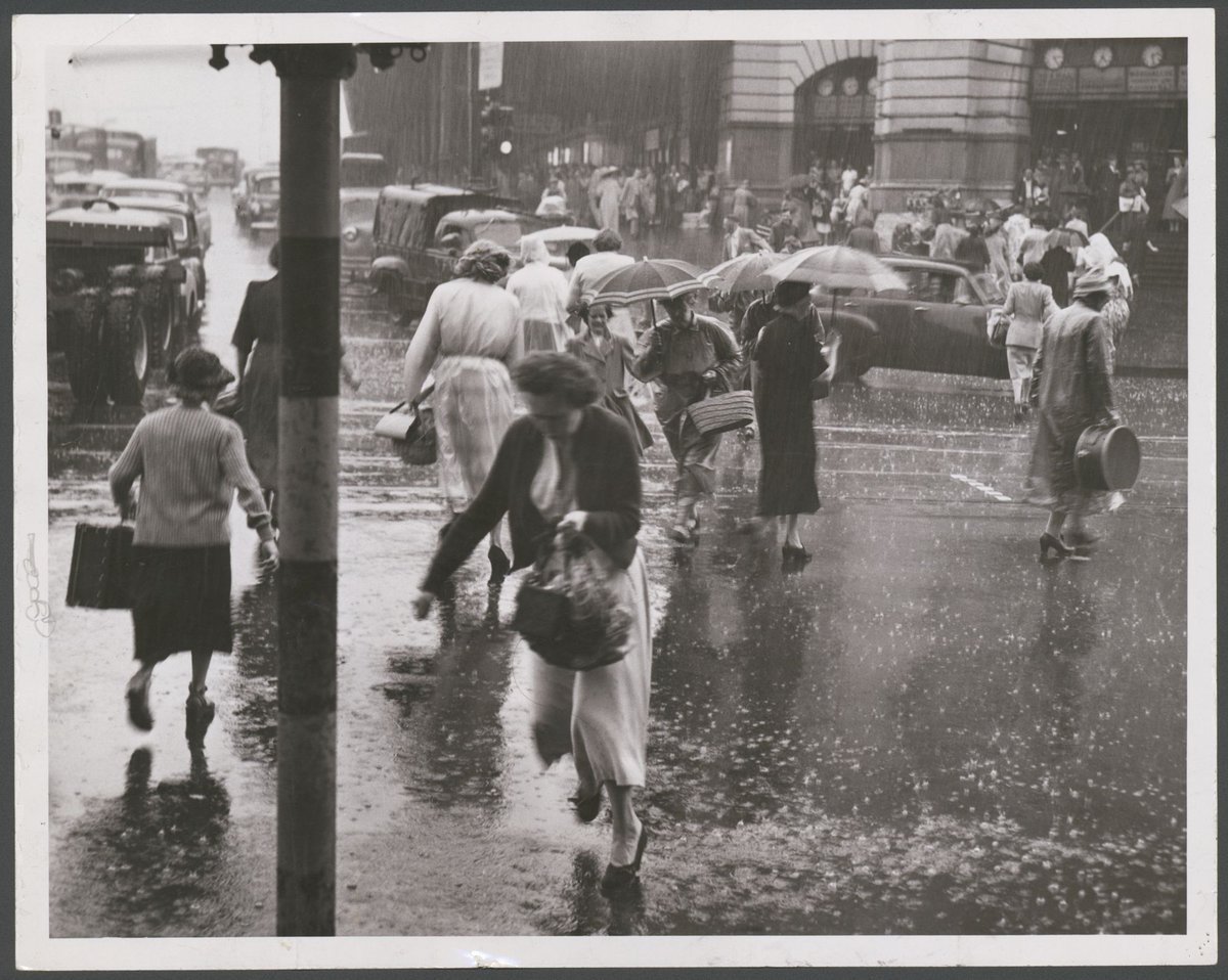 Women run from the shelter of Flinders Street Railway across the flooded streets. Many were caught in light clothes, Melbourne City (1954)