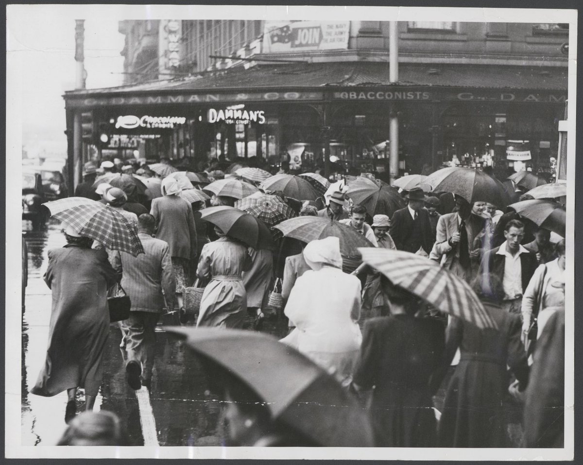 Sudden downpour in Melbourne streets. A sea of umbrellas appeared on the corner of Collins and Swanston Streets, Melbourne City (1953)