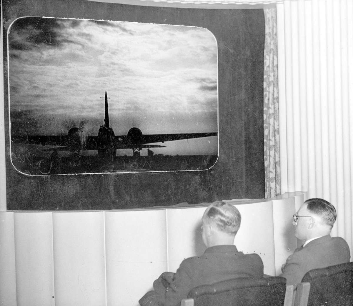 Squadron Leader C.B. Ranson of the RAAF and Mr R. Miners of Hoyts theatres, watching a preview of "Target for tonight", at the Athenaeum theatre, Melbourne (1941)