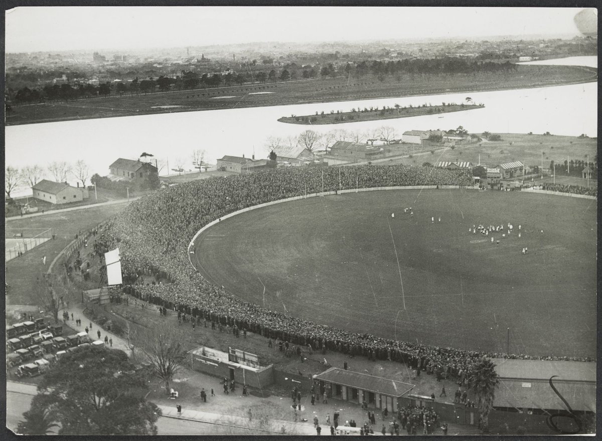 Aerial view of Albert Park Lake and the South Melbourne Cricket Ground in the foreground with a football match in progress, East Melbourne (1920–40)