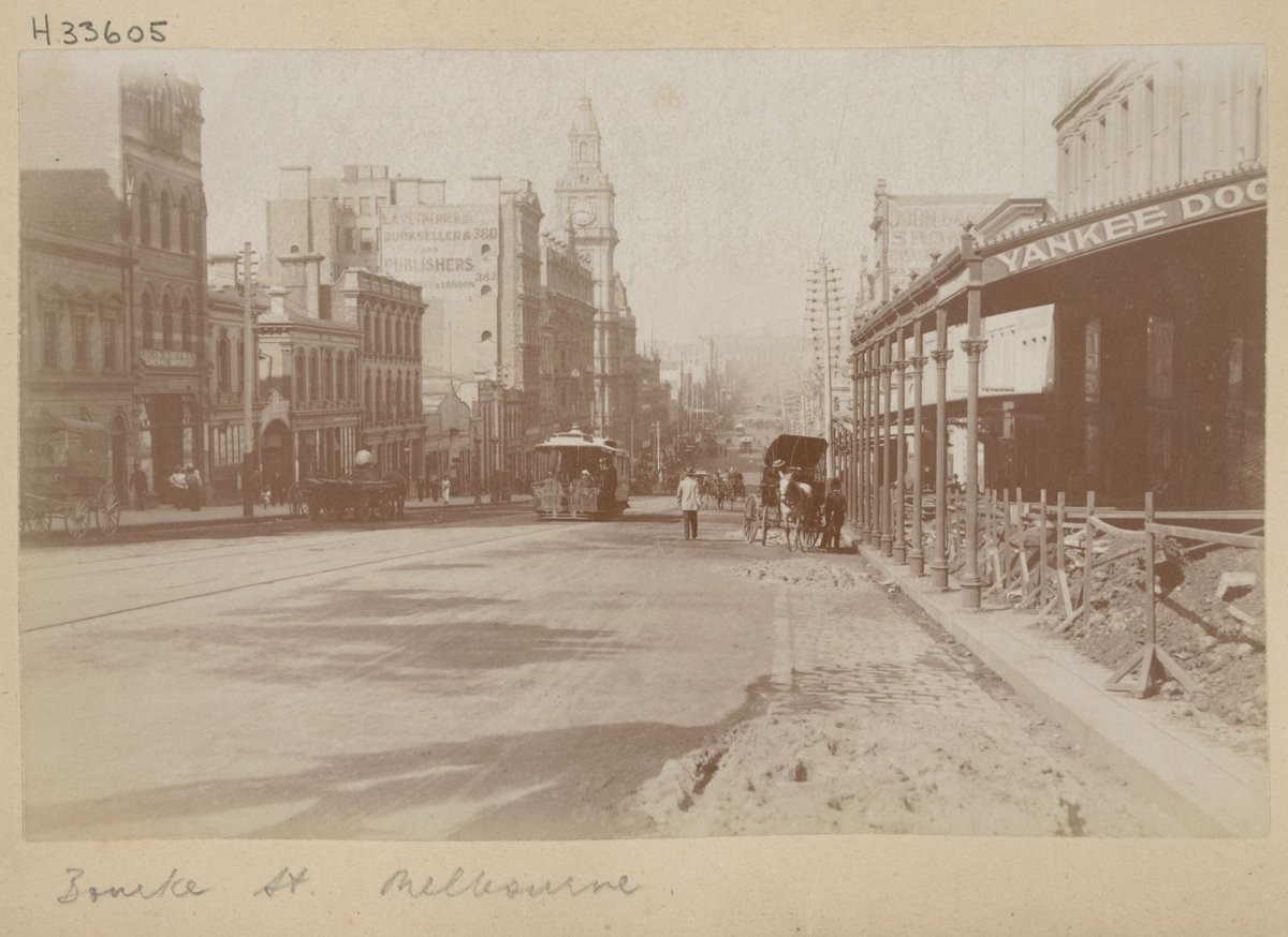 Bourke Street, Melbourne, with building rubble on footpath and cable trams and horse drawn vehicles in street, Melbourne City (1890–1900)