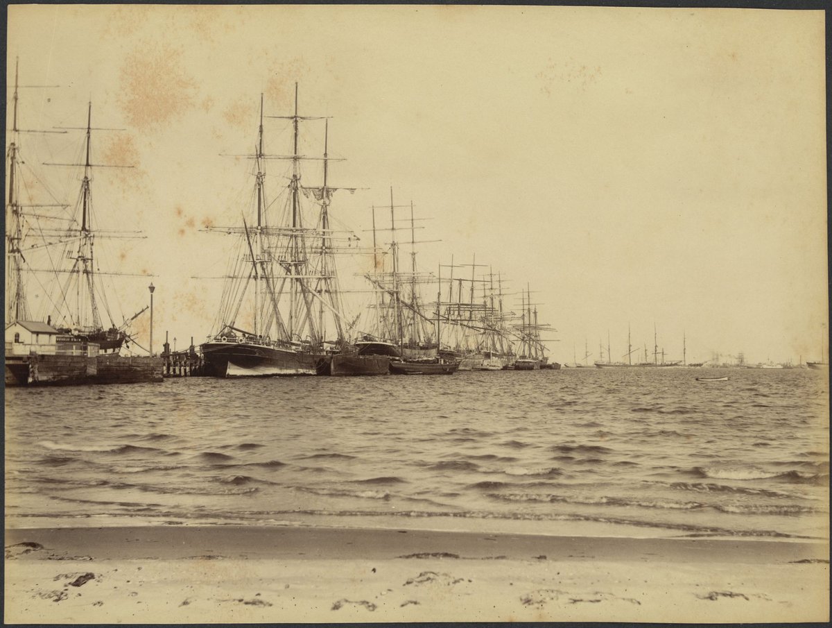 View from the beach of sailing ships at wharf and in the bay, possibly Port Melbourne and Port Phillip Bay (1888?)