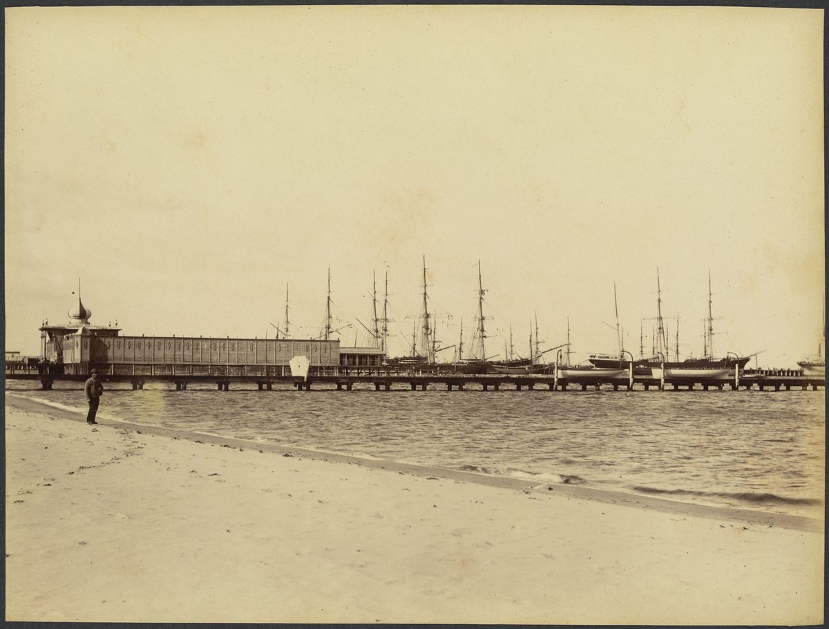 View from the beach of sailing ships at wharf, pier and baths, man standing on beach, possibly Port Melbourne (1888?)