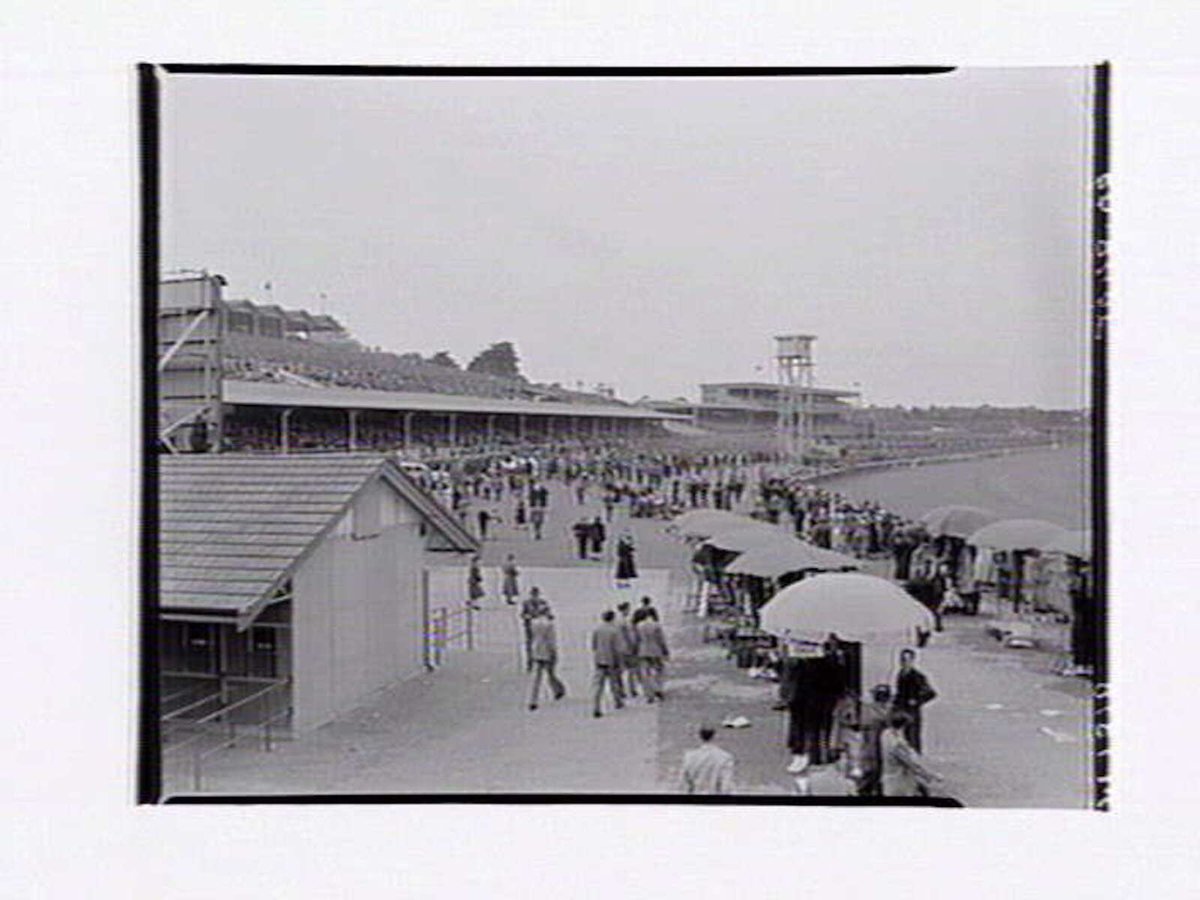 Flemington Racecourse, showing racetrack, members stand and large crowds of people (1949)