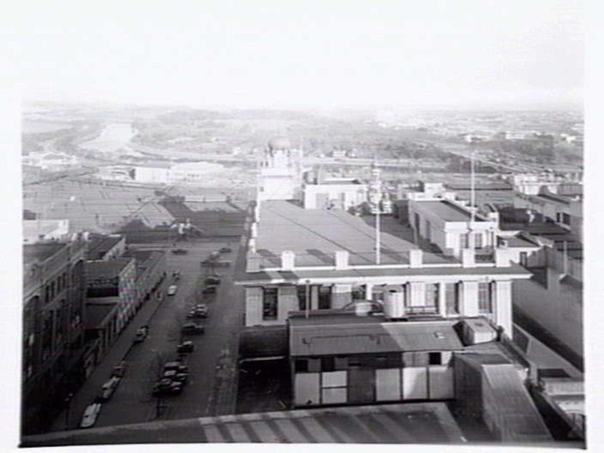 View over rooftops from corner of Russell and Flinders Streets, Melbourne, showing Flinders Street Station Rail Yards, Yarra River and Ball & Welsh Ltd, Melbourne City (c. 1943)