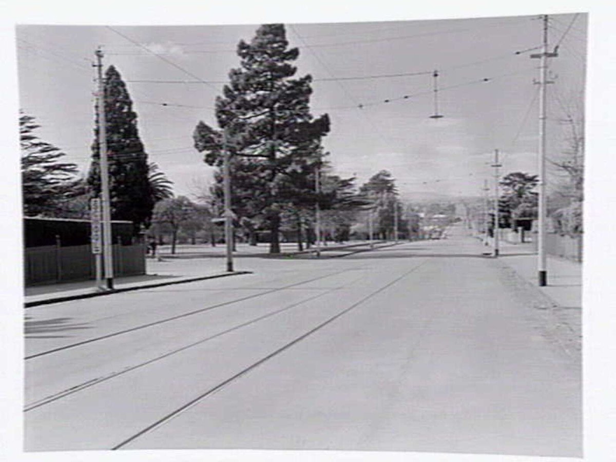 View down High Street, Malvern, the Malvern public gardens, and State School on corner of High Street and Spring Road, Malvern (c. 1950)