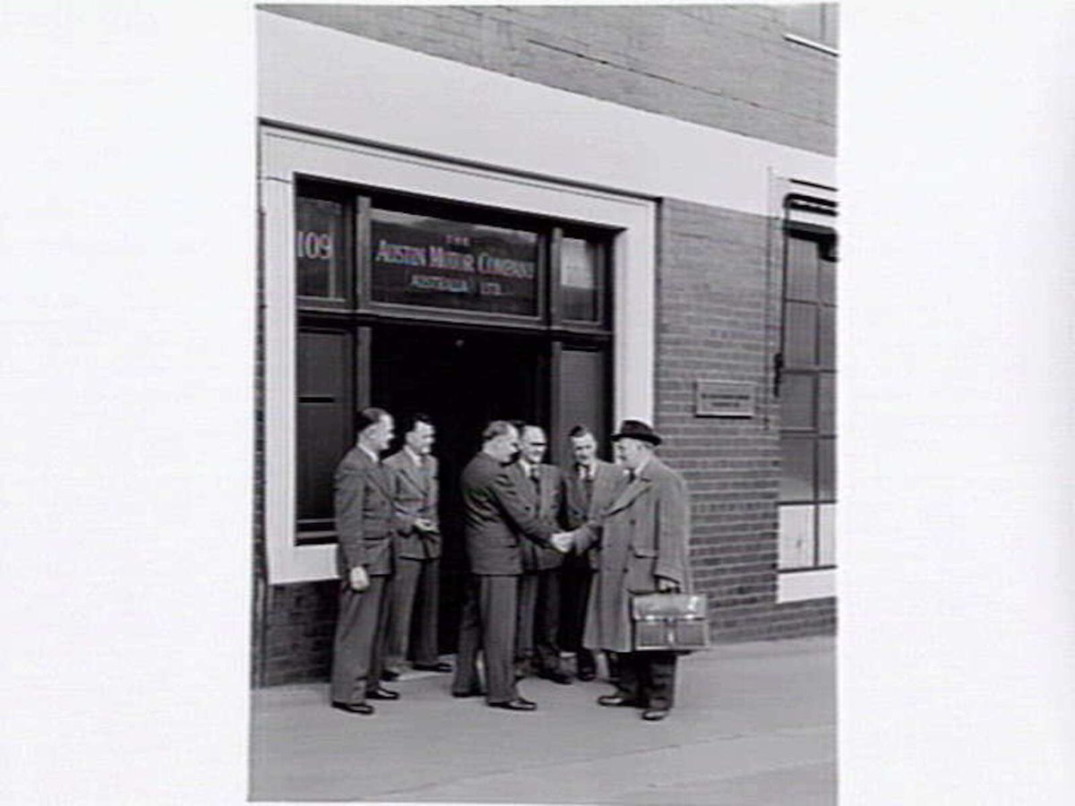Austin Motor Co., 109 Dudley St., West Melbourne, executives shaking hands, examining car body parts and checking opened crate of body components (1949)