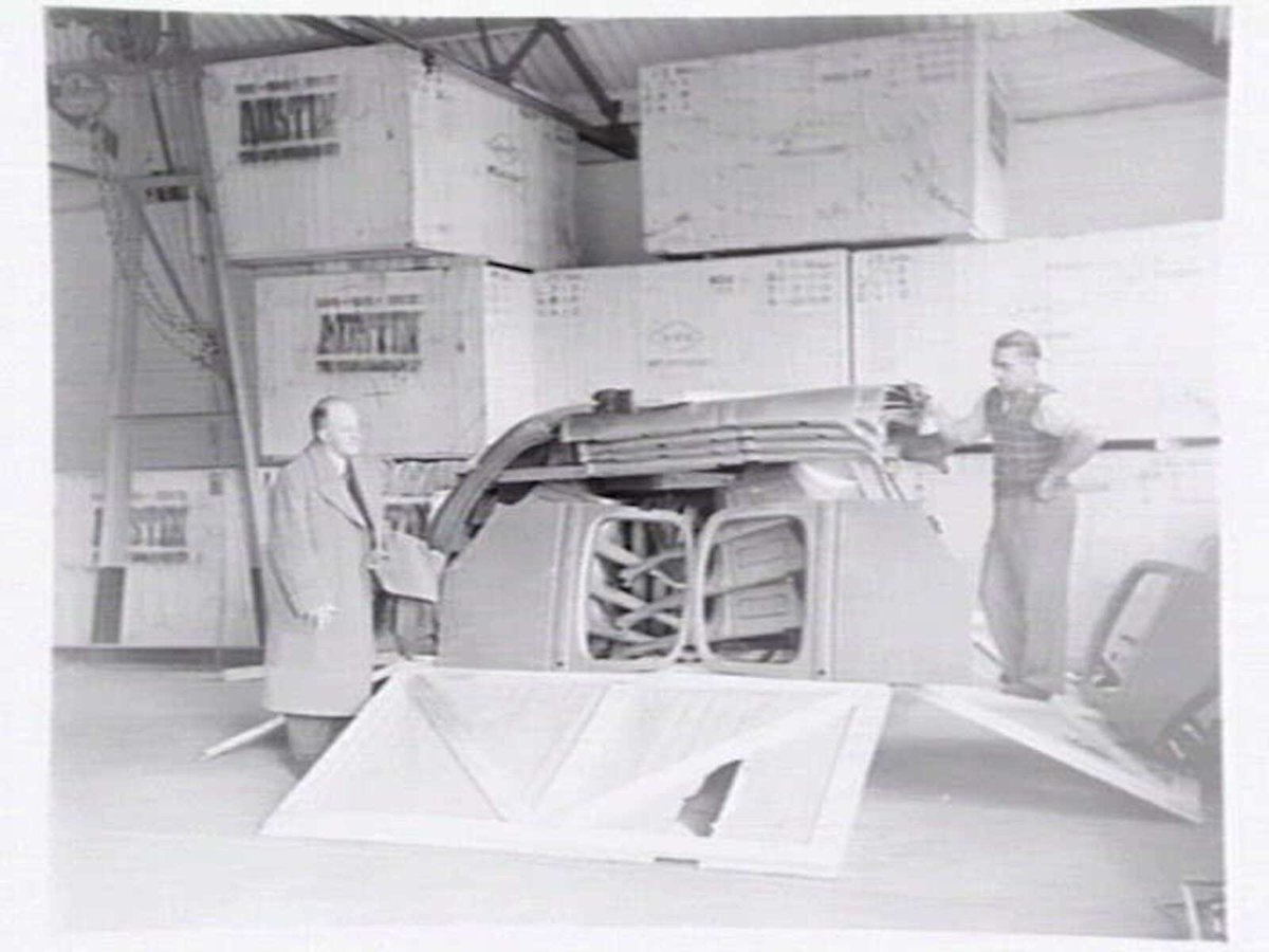 Austin Motor Co., 109 Dudley St., West Melbourne, executives shaking hands, examining car body parts and checking opened crate of body components (1949)