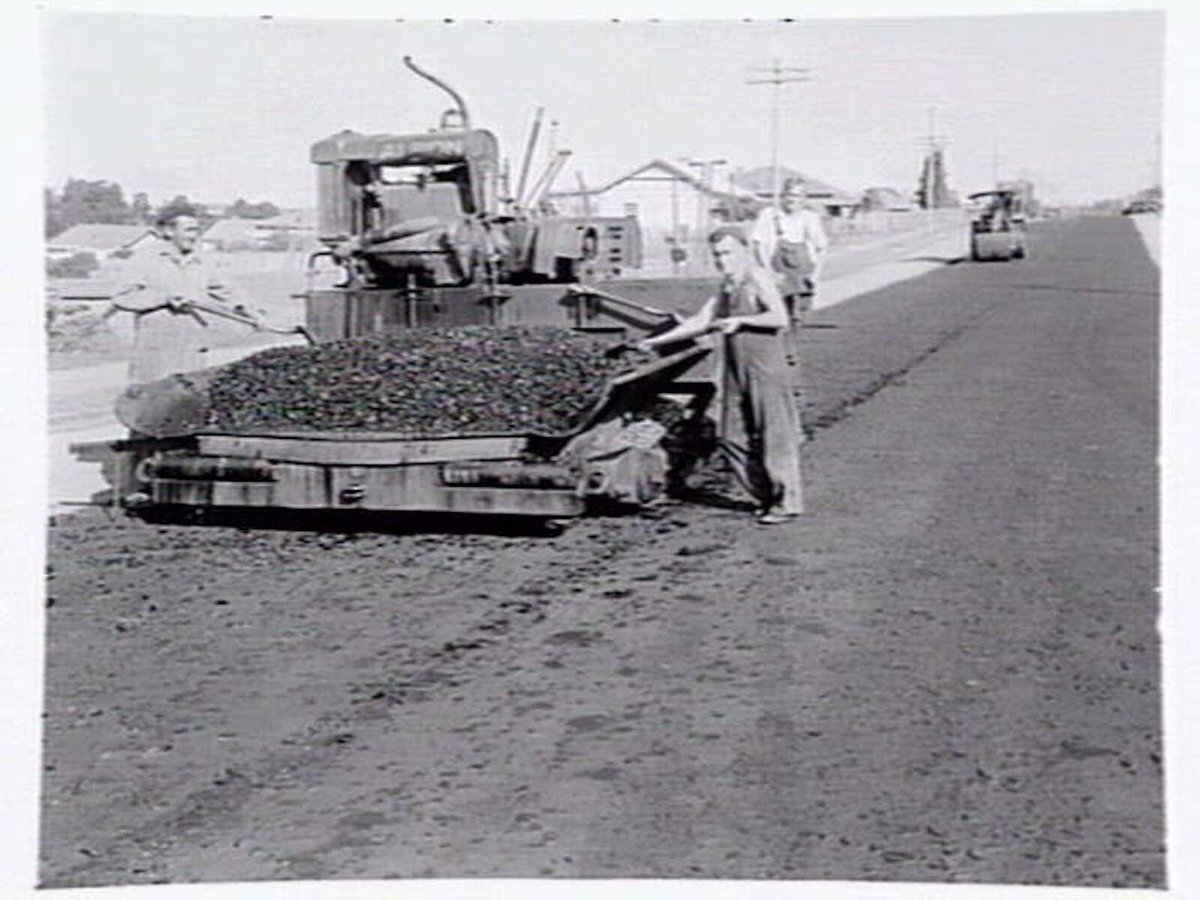 Roadmaking by Albion Quarrying P/L, showing machine laying asphalt and section of road in Heidelberg yet to be resurfaced (1950)
