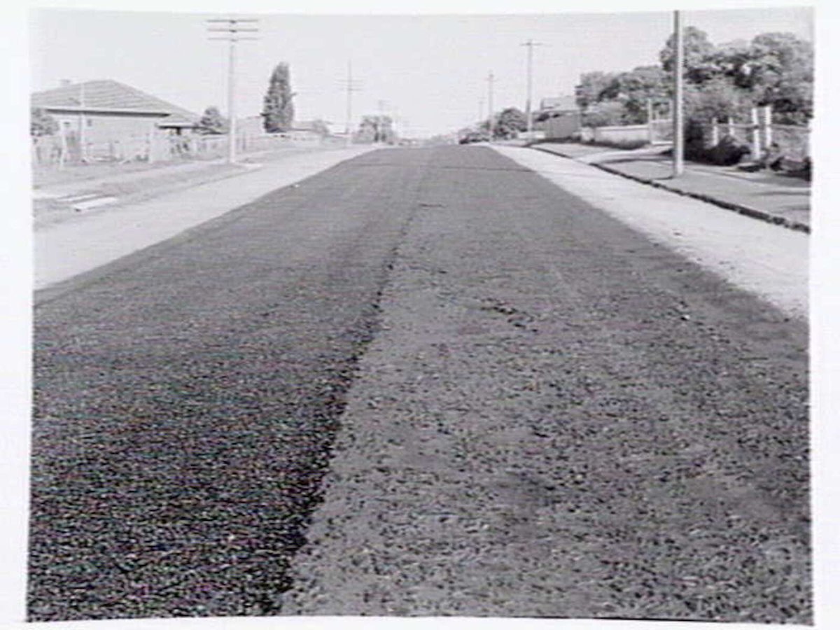 Roadmaking by Albion Quarrying P/L, showing machine laying asphalt and section of road in Heidelberg yet to be resurfaced (1950)