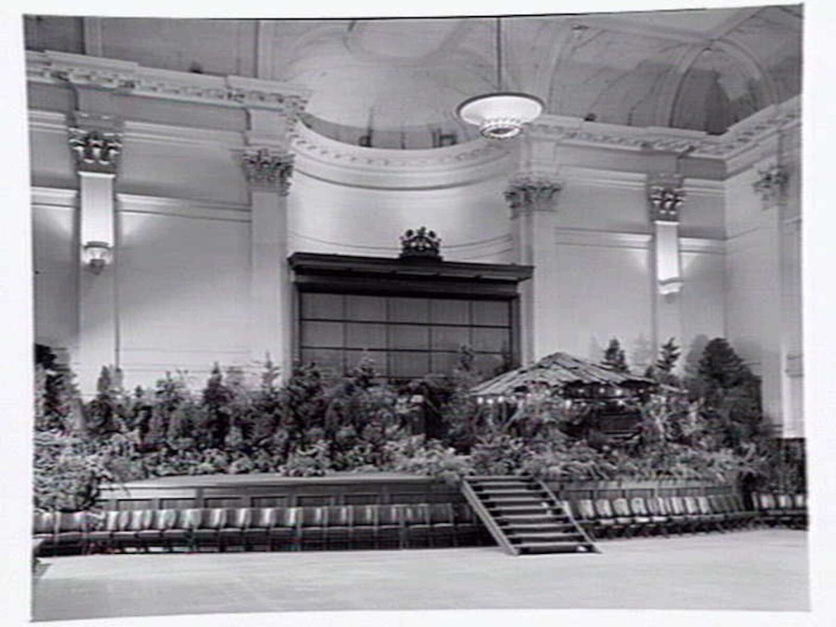 South Melbourne Town Hall, stage area decorated with plants and bark roofed hut, Melbourne City (1950?)