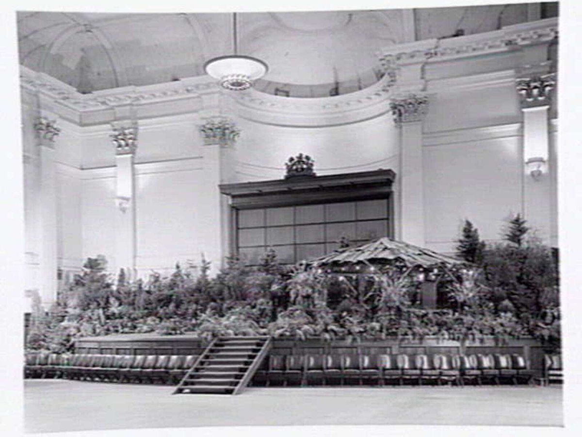 South Melbourne Town Hall, stage area decorated with plants and bark roofed hut, Melbourne City (1950?)