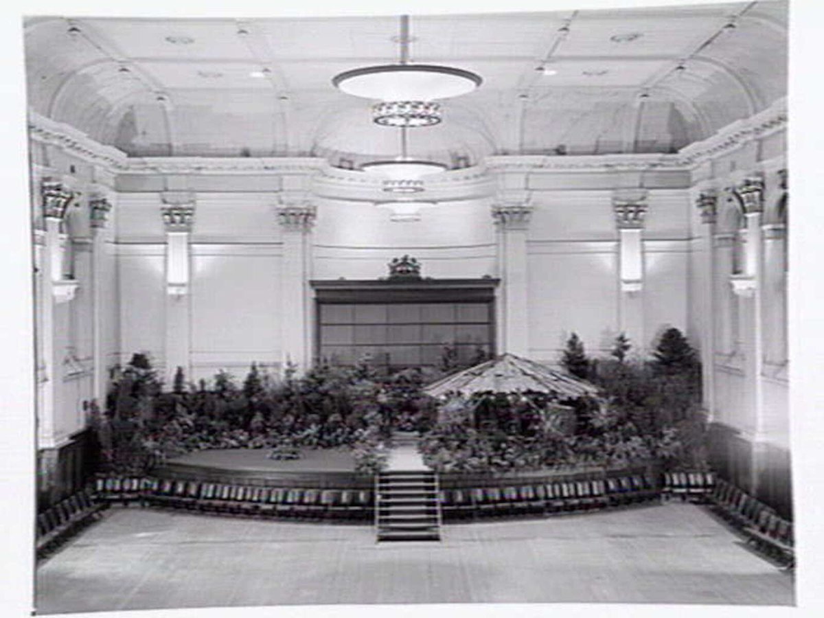 South Melbourne Town Hall, stage area decorated with plants and bark roofed hut, Melbourne City (c. 1950)