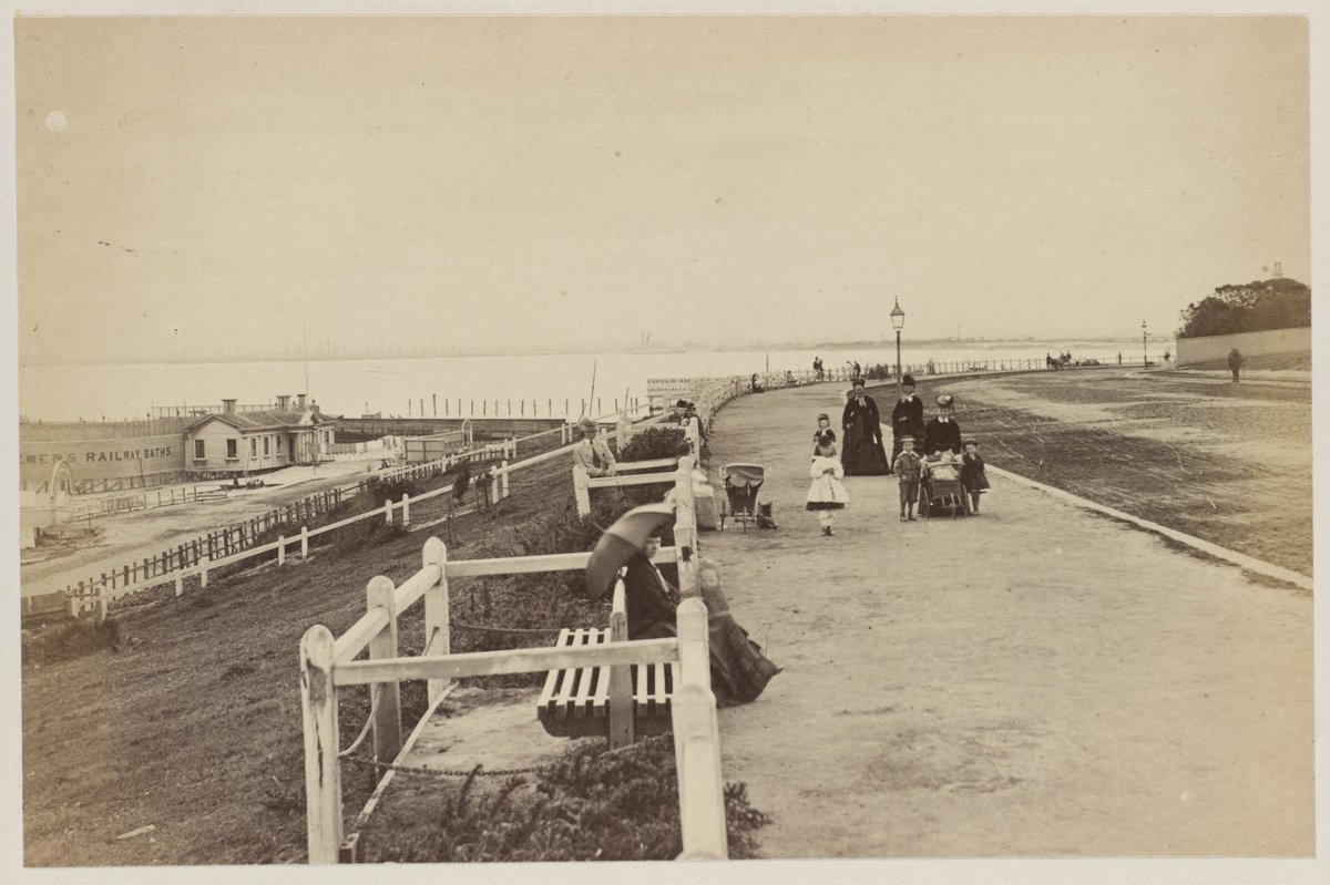 The Parade St. Kilda [The Esplanade, shows Railway Baths, women & children walking & sitting on Esplanade] [Melbourne], St Kilda (1875)