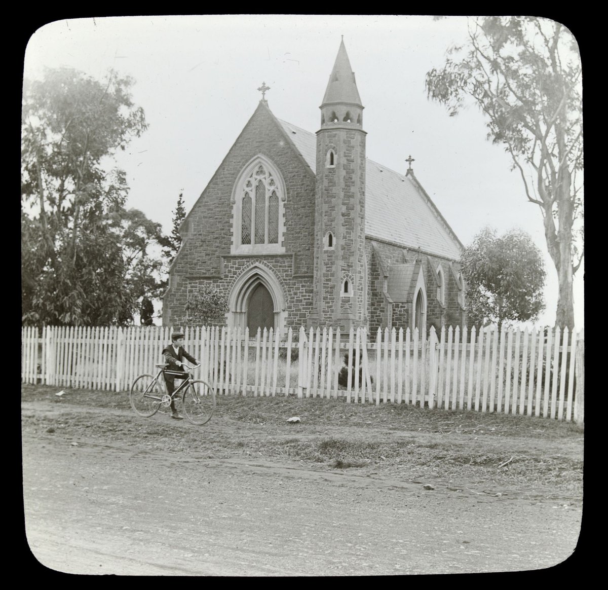 Boy with a bicycle outside St. Augustine's church, Keilor (1906–14)
