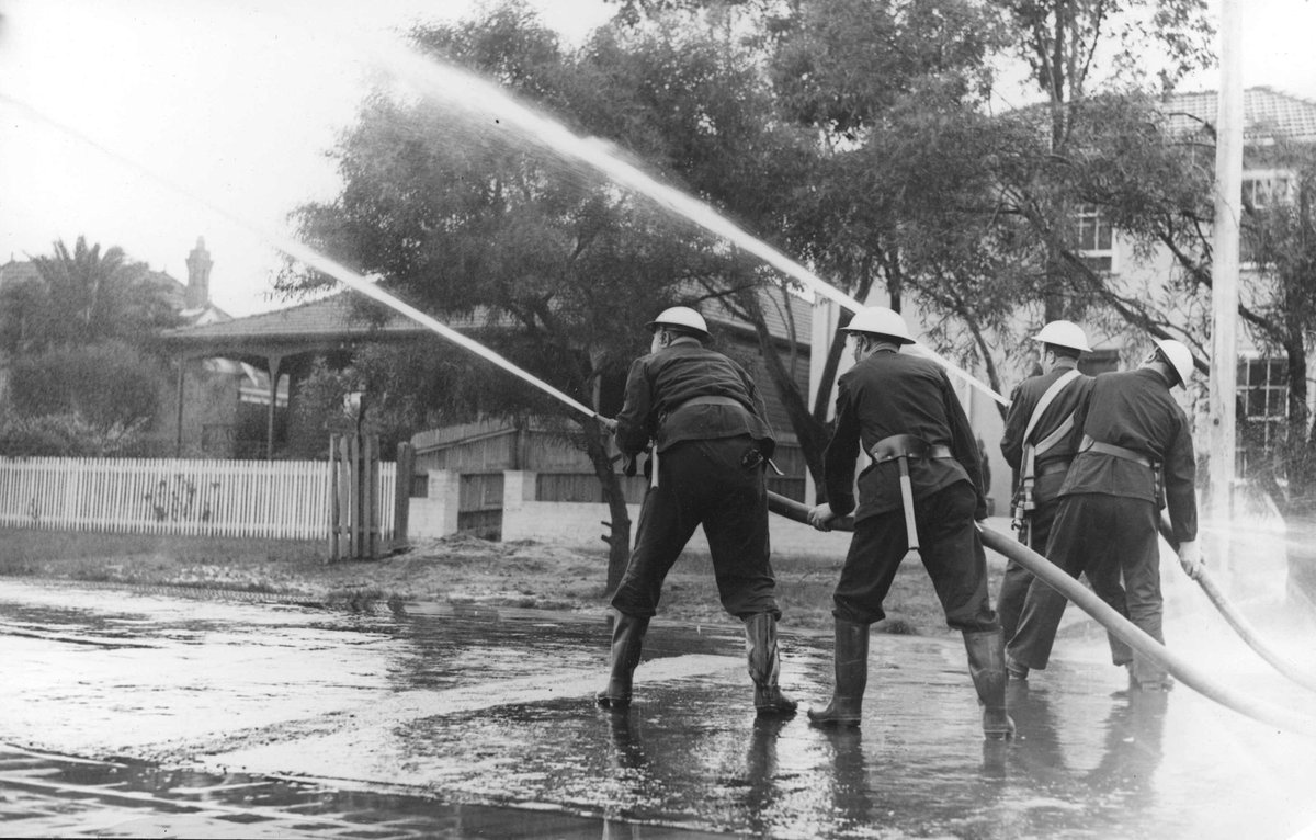 Four Auxiliary Fire Service members using firehose on Brighton street, Melbourne (1939–45)