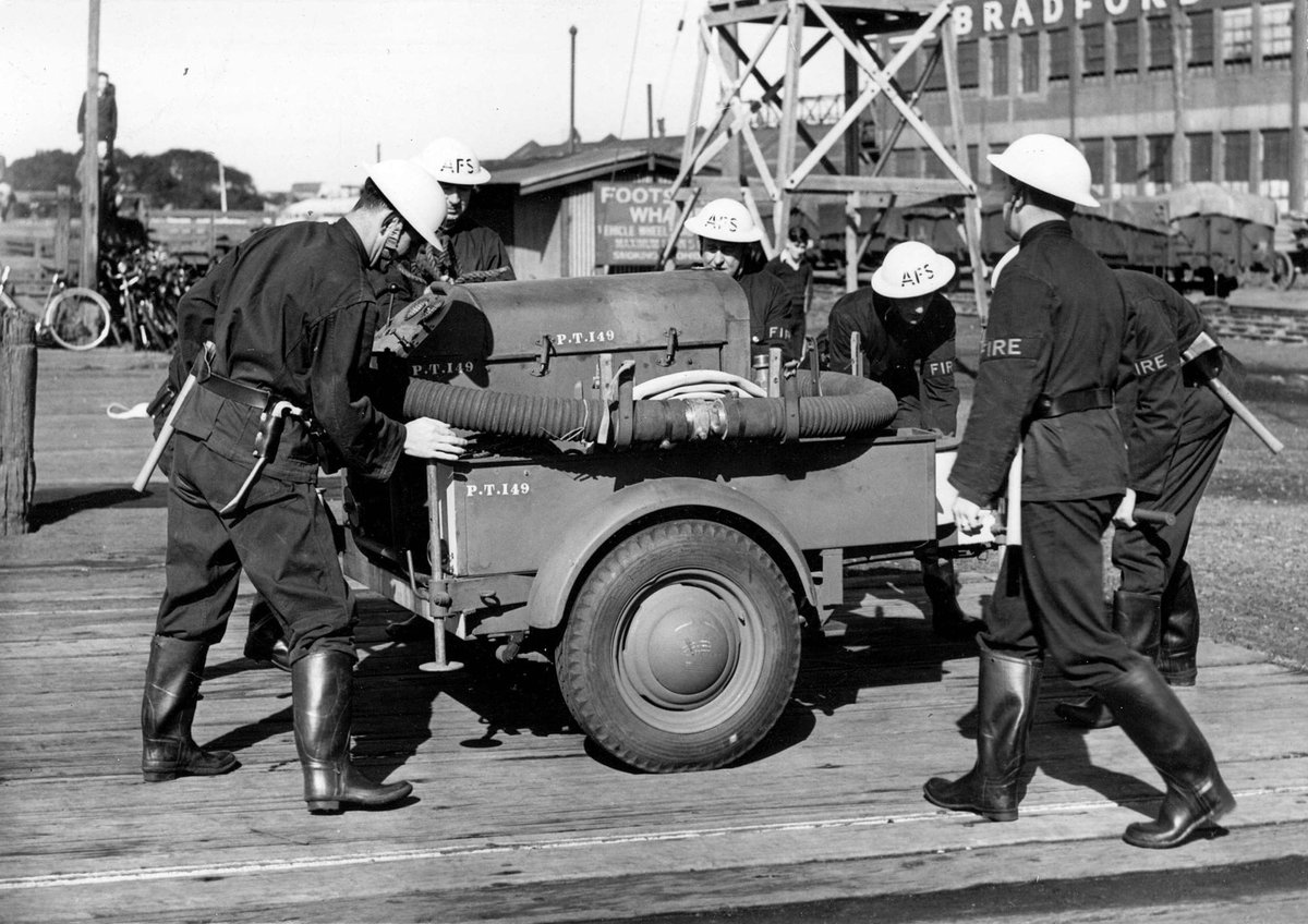 Footscray Auxiliary Firemen inspecting hose carriage and trailer pump during World War II (c. 1942)