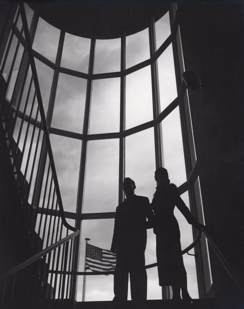 Man and woman on stairs in glass walled stairwell at Chesebrough Corporation's head office, 1970 Dandenong Road, Clayton (c. 1953)
