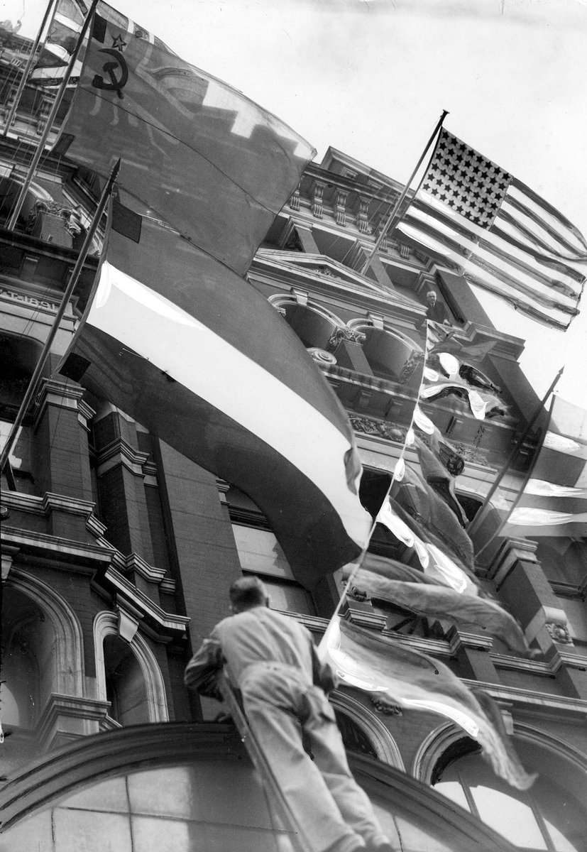Hoisting the flags of all nations on buildings in Flinders Street, Melbourne City (c. 1945)