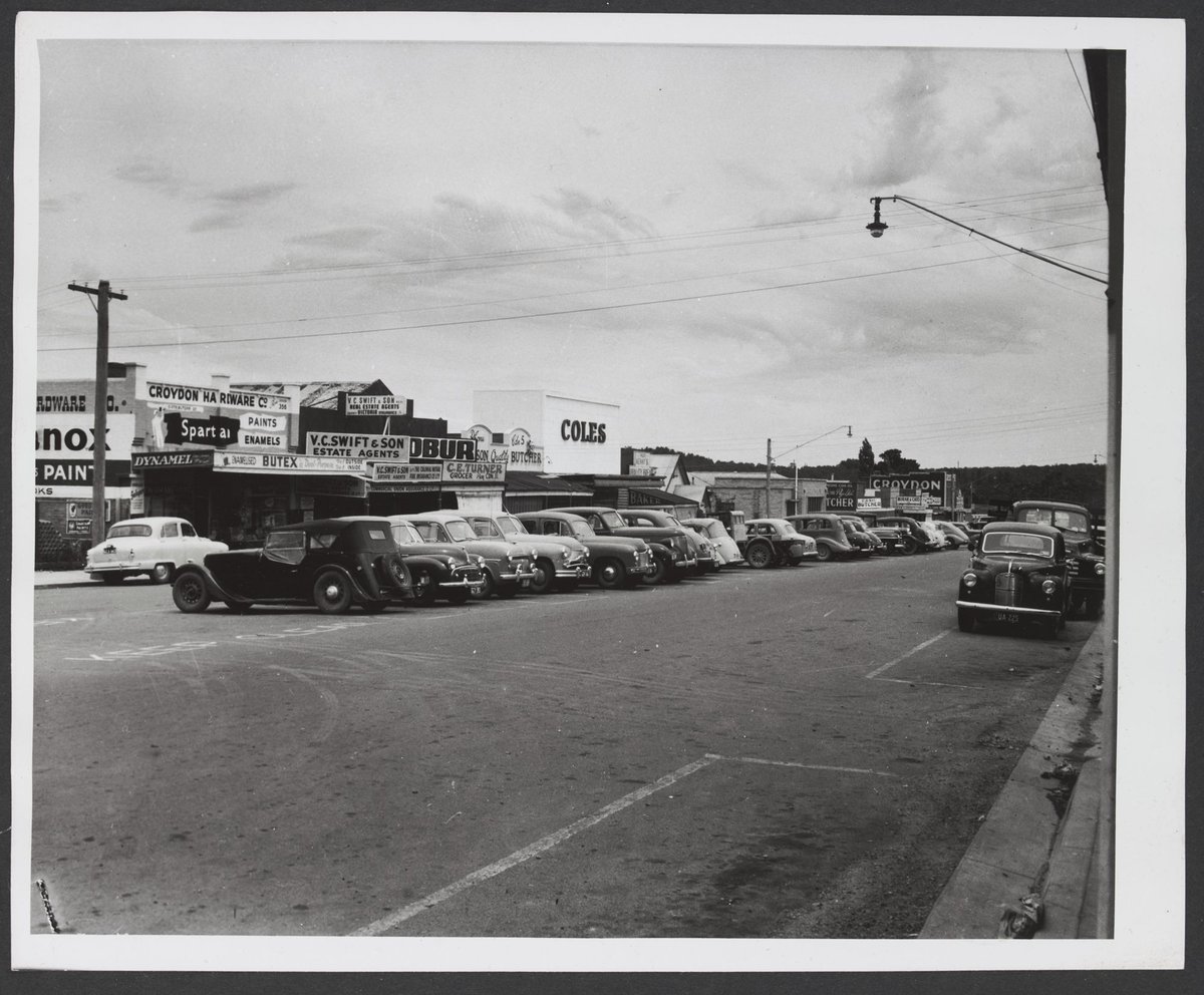 Looking across street and parked cars towards row of shops including Coles Croydon Store No. 204 (1935)