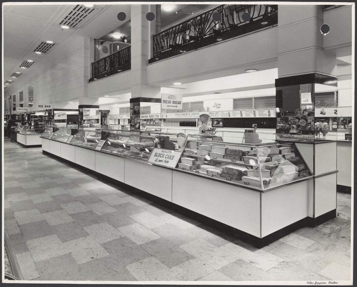 Glass cabinets displaying cakes with sandwich bar behind and cafeteria on level above Coles Bourke Street Store No. 12, Melbourne City (1940–47)