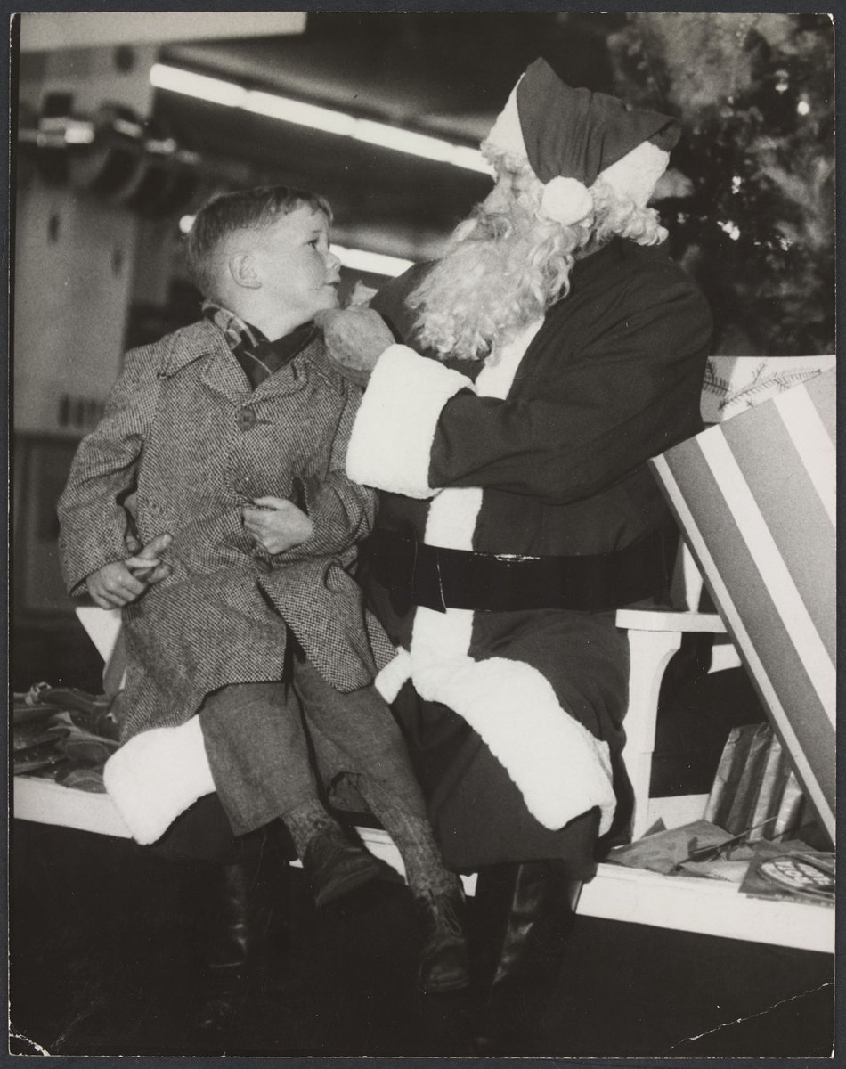 Boy sitting on "Santa's" knee inside Mantons Bourke Street store, Melbourne City (1942–51)