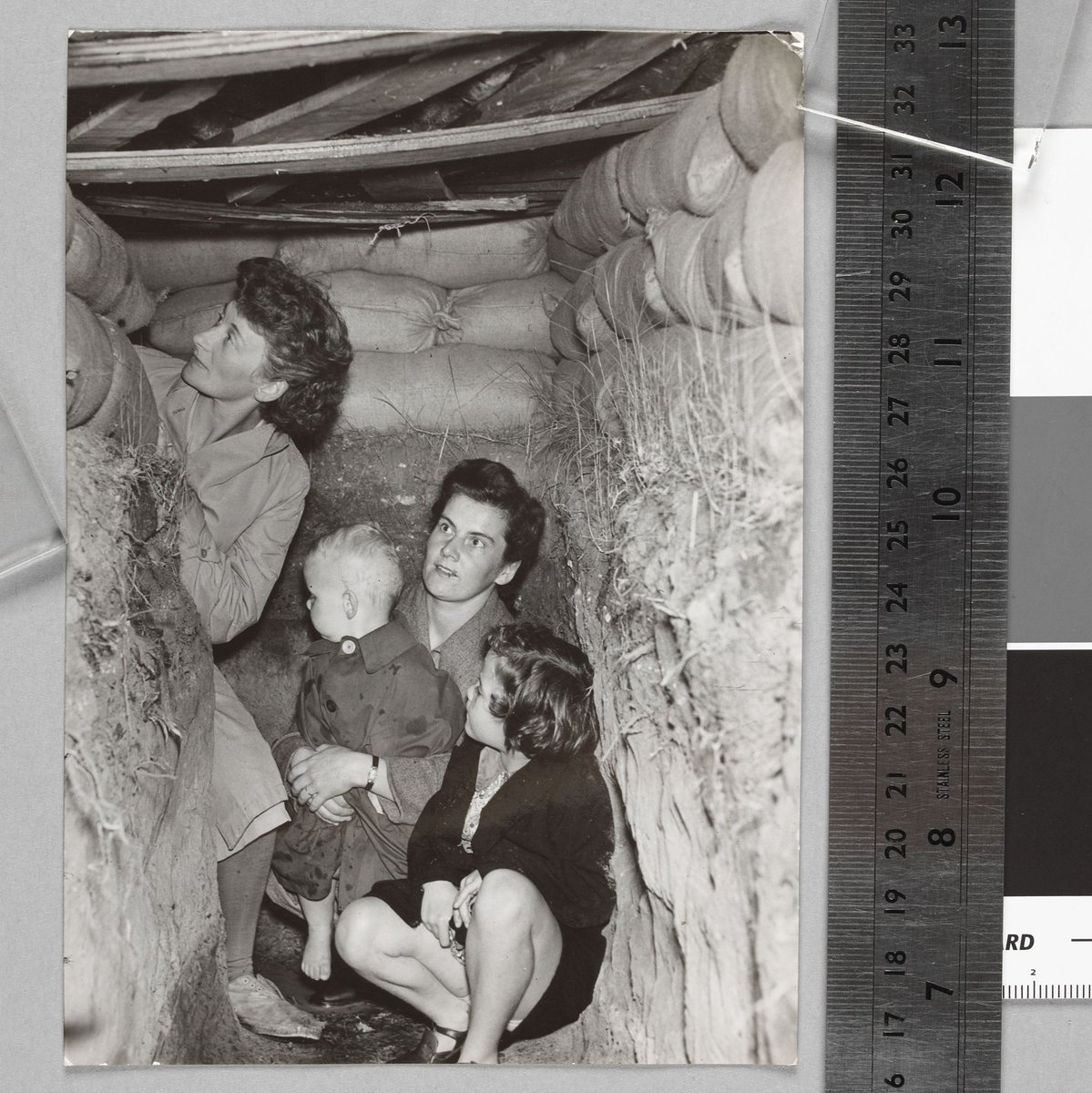 Suburban Housewives at Brighton take shelter in the backyard dug-out (c. 1942)