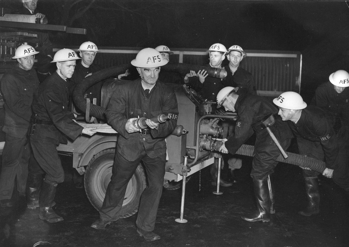 Fireman J. Godfrey of the Auxiliary Fire Service (Northcote Branch) holding fire hose attached to trailer pump (1939–45)