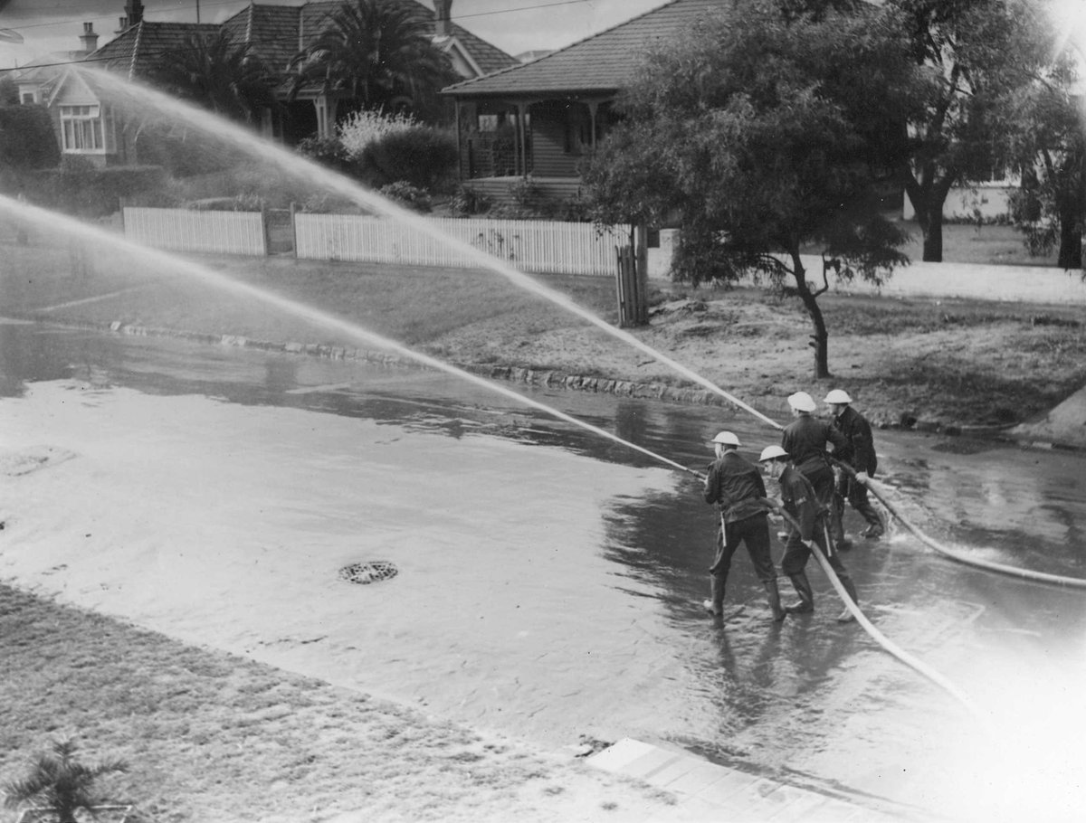 Looking down on Auxiliary Fire Service using firehose on a Brighton street, Melbourne (1939–45)