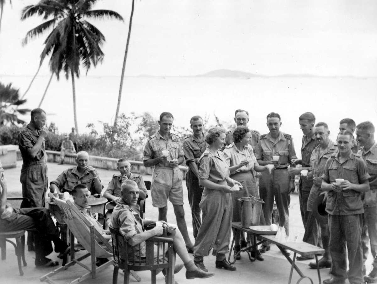 On the front verandah of the officers section at Camp 6 : Australian Red Cross workers Sheila Lane (Kew, Vic) on left and Margot Davies (West Aust) serve out tea (c. 1945)