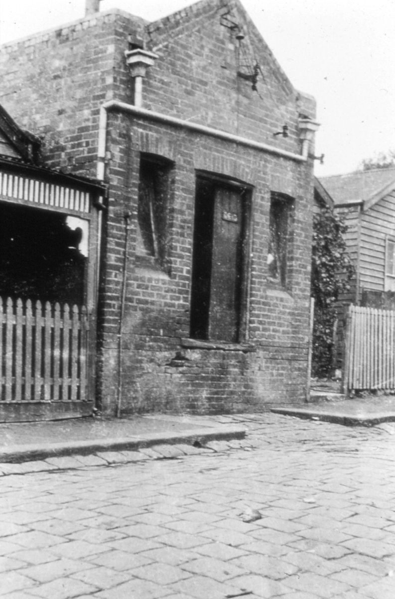 Melbourne. Brick building flanked by houses (c. 1935)