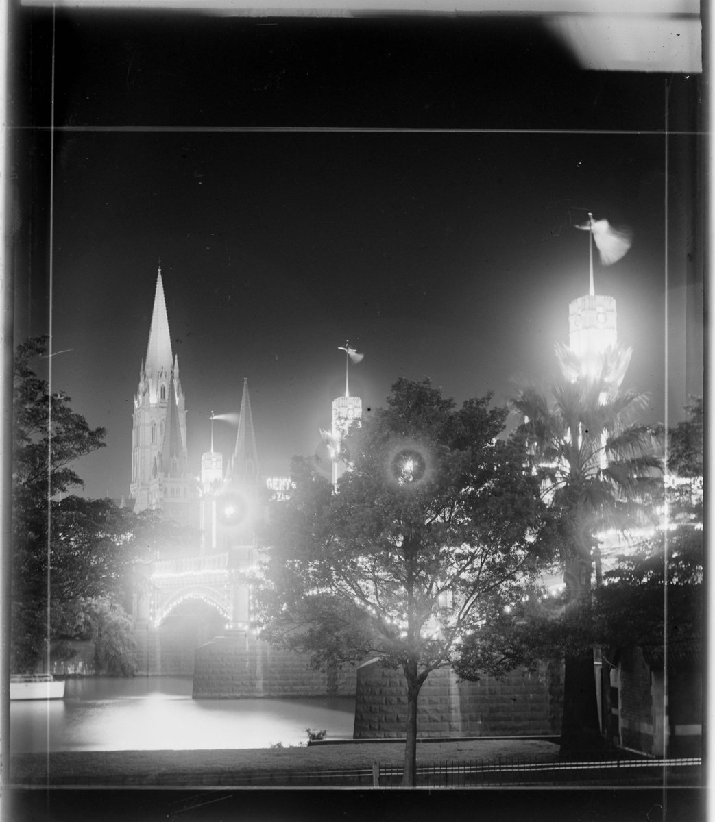 Melbourne city and illuminated Centenary pylons on Princes Bridge, taken from south side of Yarra River, where Arts Centre now stands (1934–35)