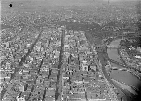 Looking east up Collins Street over City of Melbourne, including Yarra River and Flinders Street Rail Yards, c. 1948