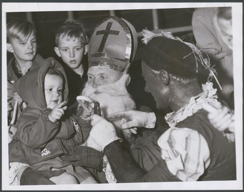 Dutch children who arrived from, Holland by K.L.M. Skymaster at Essendon had a nice surprise when they were met by Saint Nicholas ... Black Peter. Little Sonia Van Derwiok from Leiderdorp, Holland, 1952