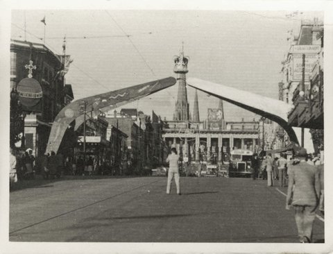 Arch of boomerangs, topped with a crown, spanning Bourke Street Melbourne, looking towards Spring Street and Parliamentary Buildings, 1930–50