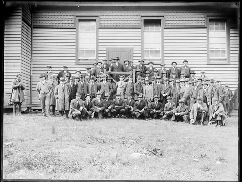 Portrait of a large group of men outside the Diamond Creek? hall, 1910–18