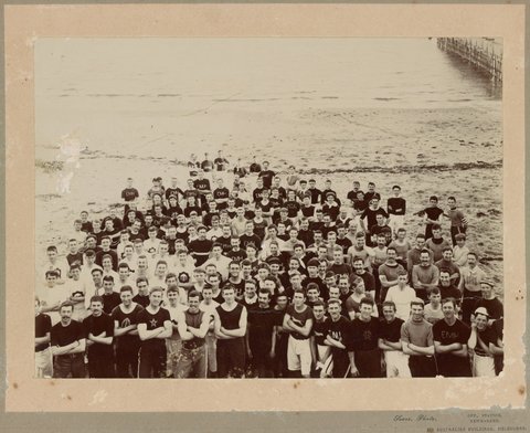 Group portrait of East Melbourne Harriers and members of other harrier clubs by the sea, c. 1905