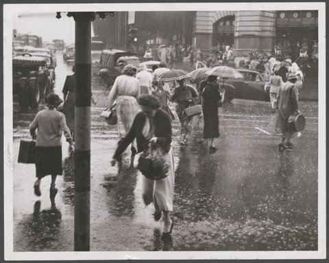 Women run from the shelter of Flinders Street Railway across the flooded streets. Many were caught in light clothes, 1954
