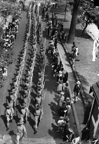 Crowd of people watching soldiers marching on road, possibly beside Yarra River, 1940–45