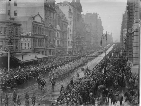 Looking down Collins Street, Melbourne, from intersection at Elizabeth Street, showing World War 1 soldiers marching from Spencer Street. Crowds lining street, 1910–20