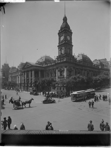 Melbourne Town Hall on corner of Collins and Swanston Streets, showing cable tram, horse drawn vehicle, car and pedestrians, 1910–20