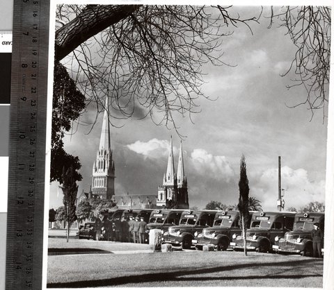 [New ambulances and their drivers lined up in Cathedral Place, Melbourne, with St. Patrick's Cathedral in the background], c. 1941