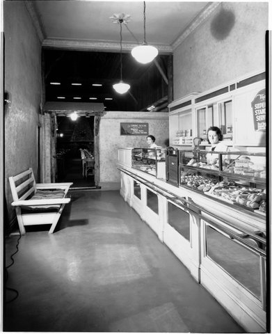 Interior of large restaurant opposite Melbourne Town Hall, Swanston Street, showing waitresses behind food displayed at counter, 1940s