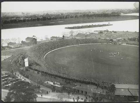 Aerial view of Albert Park Lake and the South Melbourne Cricket Ground in the foreground with a football match in progress, 1920–40
